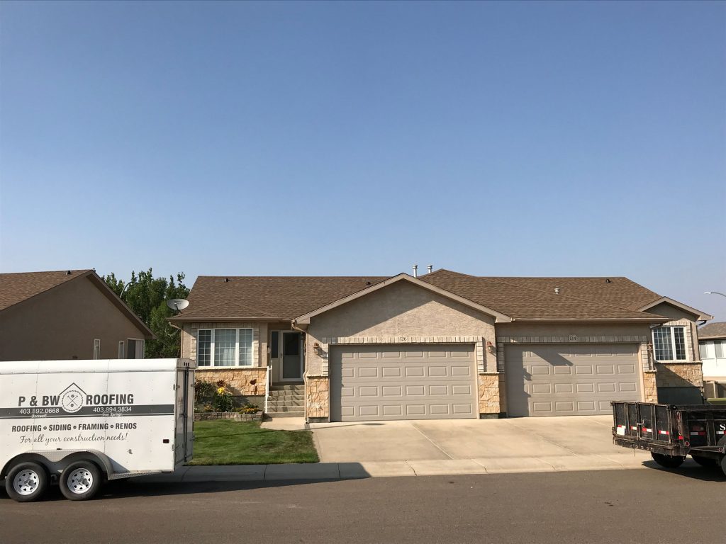 Completed residential roof with P & BW Roofing trailer in the picture to the left side.