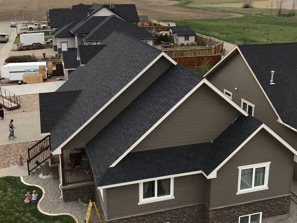 Roofing completed for multiple houses in a new development community. Black shingles.
